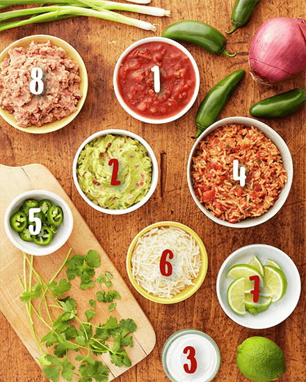ingredients for fajita servings such as salsa, rice, guacamole, meat, cheese, sliced lime etc.